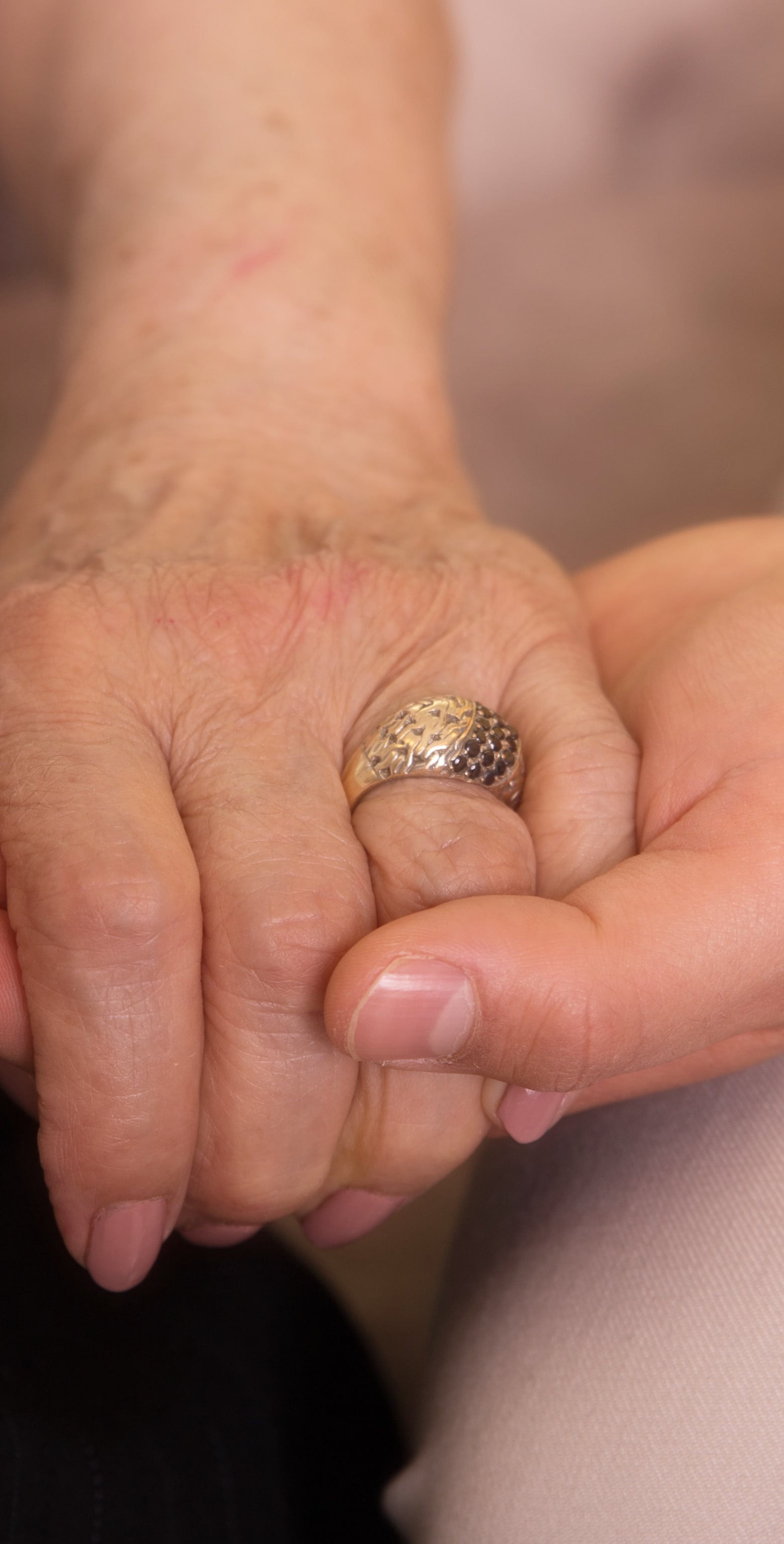 Nahaufnahme: Die Hand einer Seniorin liegt in der Hand einer Pflegekraft